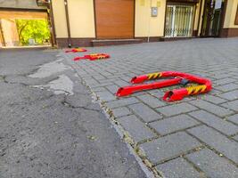 A red and yellow parking meter is on the ground in front of a building. The parking meter is broken and has a yellow and black stripe photo