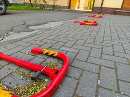 A red parking meter with a yellow stripe is on the ground. The parking meter is broken and has a lock on it photo