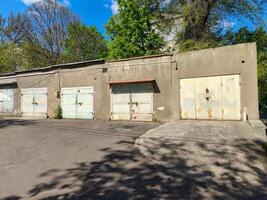 A row of old, rusted garage doors sit in front of a building. The garage doors are all different sizes and colors, and they are all open. The scene is quiet and peaceful, with no one around photo