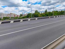 A long, empty highway with a few trees in the background. The sky is cloudy and the sun is not visible photo