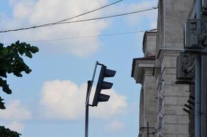 A traffic light is upside down and the sky is cloudy. The building behind the traffic light is tall and has a red roof photo