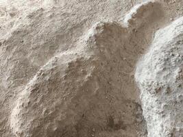 A pile of sand with a small object in the middle. The sand is brown and the object is green photo