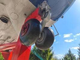 The landing gear of an airplane, with the wheels being red and black. The scene is set against a blue sky, creating a sense of calm and serenity. The contrast between the bright blue sky photo