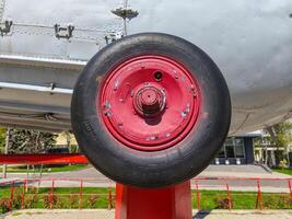 A red and black tire is on a red pole. The tire is old and worn, and it is leaning against a fence. The scene is quiet and peaceful, with the only sound being the rustling of the grass photo