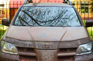 A car with a skull on the hood and a skull on the grill. The car is dirty and has a rusty appearance photo