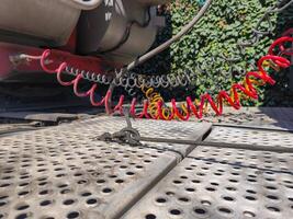 A red and yellow tire is attached to a chain. The chain is wrapped around the tire and is connected to a red and yellow hose. The tire is on a metal surface photo