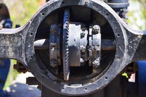 The inside of a machine with a black gear. The gear is surrounded by bolts and screws, and it is a part of a larger mechanism. Scene is one of curiosity and intrigue photo