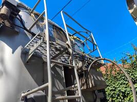 A metal container has a ladder attached to it. The ladder is connected to the container by a chain photo