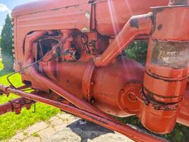 A red tractor with a black engine. The engine is old and rusty. The tractor is parked in a grassy area photo