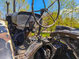 A tractor with a black steering wheel and a black dashboard. The tractor is old and rusty. The image has a nostalgic and somewhat melancholic mood photo