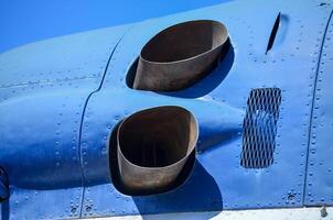 The blue airplane has a damaged exhaust pipe, which is located on the side of the plane. The pipe is rusted and he is in poor condition photo