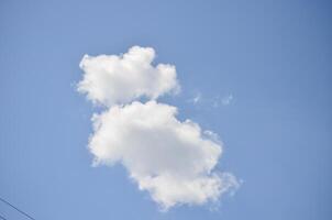 A cloud in the sky with a blue sky background. The cloud is shaped like a person. The sky is clear and bright photo