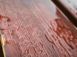 The wood is wet and has a reddish hue. The water droplets on the wood create a sense of movement and life photo