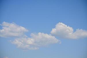 The sky is blue and clear with a few clouds scattered throughout. The clouds are small and fluffy, giving the sky a light and airy feel. Scene is calm and peaceful, with the blue sky photo