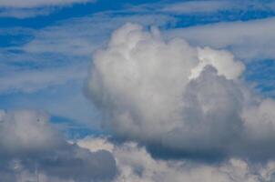 A large cloud in the sky with a blue sky background. The cloud is white and fluffy photo