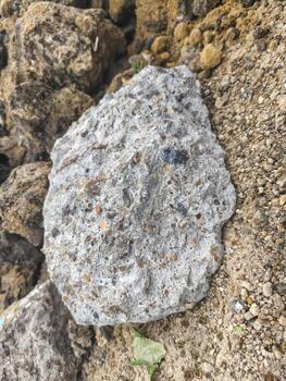 A large rock sits on a dirt field. The rock is grey and has a rough texture. The field is barren and desolate, with no signs of life. Concept of loneliness and isolation photo