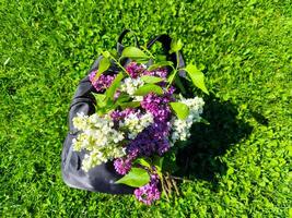 A backpack is covered in flowers, including purple and white lilies. The scene is set in a lush green field, with the flowers adding a touch of color and life to the natural surroundings photo