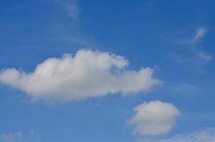 The sky is blue and clear with a few clouds scattered throughout. The clouds are small and fluffy, giving the sky a light and airy feel photo