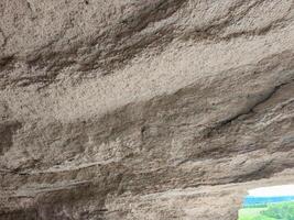 A rocky surface with a lot of cracks and crevices. The surface appears to be made of stone and has a rough texture. The cracks and crevices give the impression of a rugged and uneven terrain photo