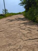 A path with a lot of cracks and dirt. The path is not very well maintained photo