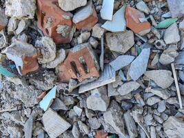 A pile of rubble with a brick in the middle. The brick is missing a piece. The pile of rubble is made up of broken bricks and other debris photo