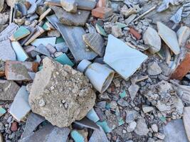 A pile of rubble with a white pipe sticking out of it. The pile of rubble is made up of broken tiles, bricks, and other debris photo