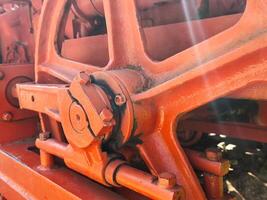 The red wheel is rusty and has a lot of bolts. It is old and worn out. The image has a vintage feel to it photo