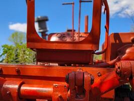 A red tractor with a blue sky in the background. The tractor is old and rusty. The blue sky in the background gives a sense of calmness and serenity photo