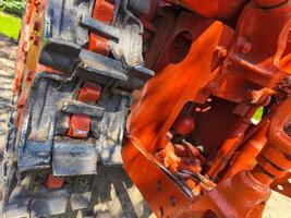 A red tractor with a black chain. The chain is rusty and worn. The tractor is parked in a field photo