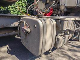 A dirty truck engine with a red and white hose attached to it. The hose is positioned on the side of the engine and is connected to a red and white container photo