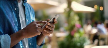 The young person engaged with a smartphone in an outdoor cafe setting. photo