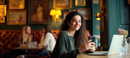 The smiling woman enjoying coffee while using her phone in a cozy cafe. photo