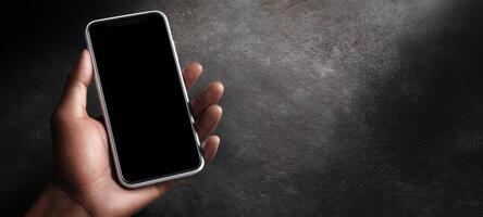The smartphone held in a hand against a textured background. photo