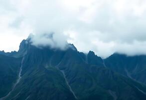 very tall mountain with some clouds in the sky photo