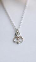 A silver necklace with a heart and a small flower photo