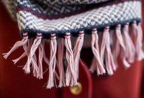 A scarf with fringes and a red coat photo
