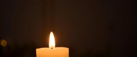 lit candle in the dark with a blurry background photo
