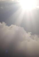 plane flying in the sky with the sun shining through the clouds photo