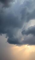 A dark cloud is seen in the sky with the sun shining through photo