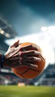A person holding an orange football ball in front of a stadium photo