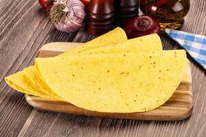 Three tortillas on a cutting board with other ingredients photo