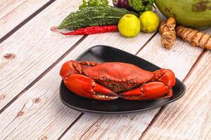 A plate of crabs, vegetables and other food on a wooden table photo