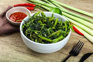 A bowl of green vegetables and a fork on a table photo
