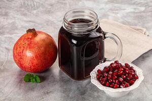 A glass jar with a pomegranate and a bowl of pomegranate photo