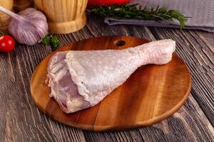 A raw chicken on a wooden cutting board with vegetables photo