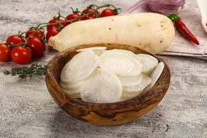 A wooden bowl with sliced potatoes and tomatoes photo