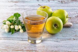 A glass of apple juice and some green apples photo