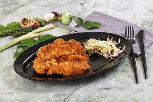 Fried chicken on a black plate with vegetables and a knife photo