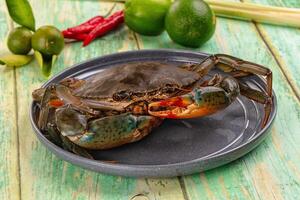 A crab on a plate with some limes and peppers photo