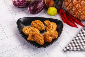 Fried chicken in a black dish on a white table photo